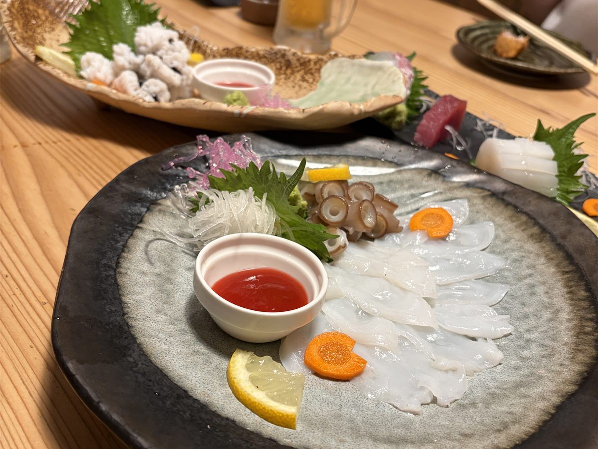 お刺身の盛り合わせ。白身の薄造りとマグロ、イカが大皿に並ぶ。