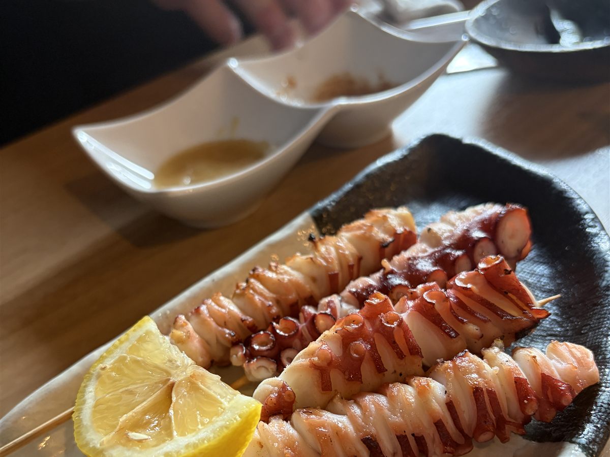 炭火で焼いたタコの串焼き。レモンが添えられている。